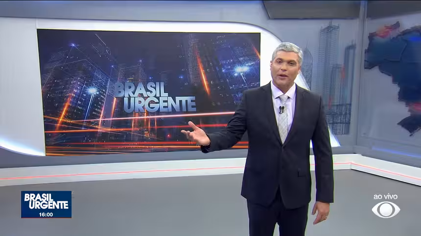 Joel Datena em pé no centro do cenário do Brasil Urgente