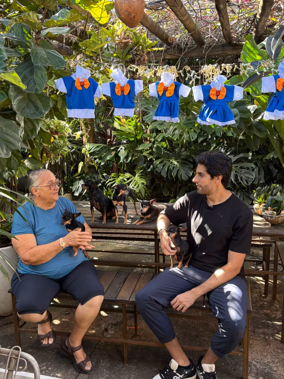 Julinho conversa com a costureira sentados e um quintal