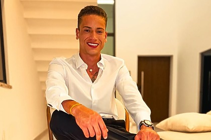 Manim Vaqueiro em foto posada, com uma perna sobre a outra