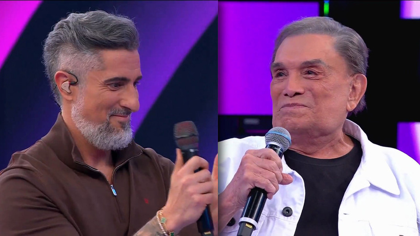 Marcos Mion aplaude Dedé Santana que olha para o apresentador emocionado no palco do Caldeirão