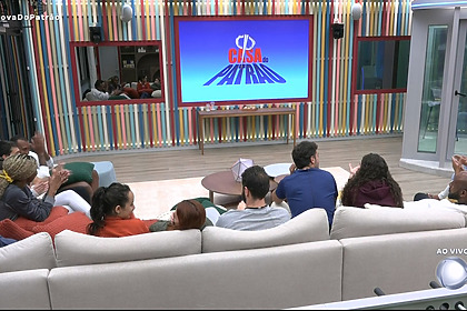 Participantes da Casa do Patrão olham para o telão após descobrirem como vai funcionar as novas regras do reality show