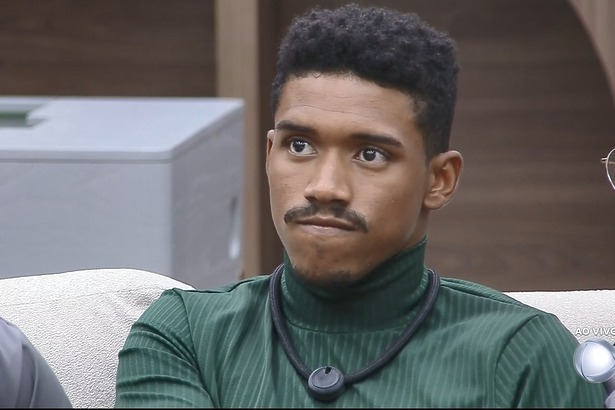 Thiago com semblante triste no sofá da Casa Do Patrão poucos minutos antes de ser eliminado. Ele veste uma camisa verde