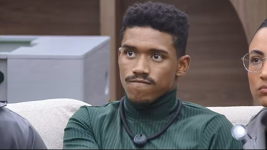 Thiago com semblante triste no sofá da Casa Do Patrão poucos minutos antes de ser eliminado. Ele veste uma camisa verde