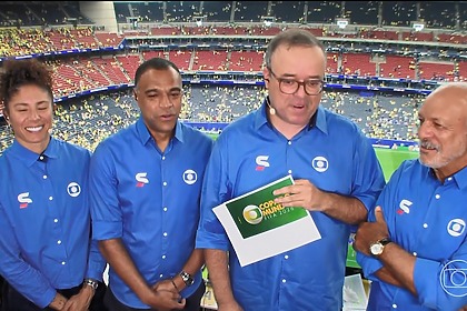 Equipe Da Globo em pé na bancada de transmissão do estádio na transmissão do jogo Brasil x Japão na Copa Do Mundo 2026