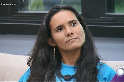 Morena com semblante triste olha para o telão da sala da Casa do Patrão antes de ser eliminada