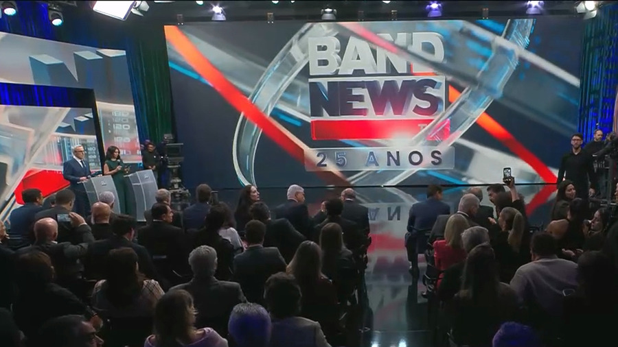 Plateia de convidados em frente ao telão do BandNews TV com o logo dos 25 anos da emissora