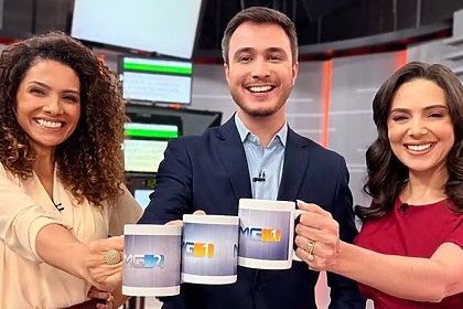 Aline Aguiar, Sérgio Marques e Mara Pinheiro posando sorrindo e segurando canecas dos telejornais da Globo Minas
