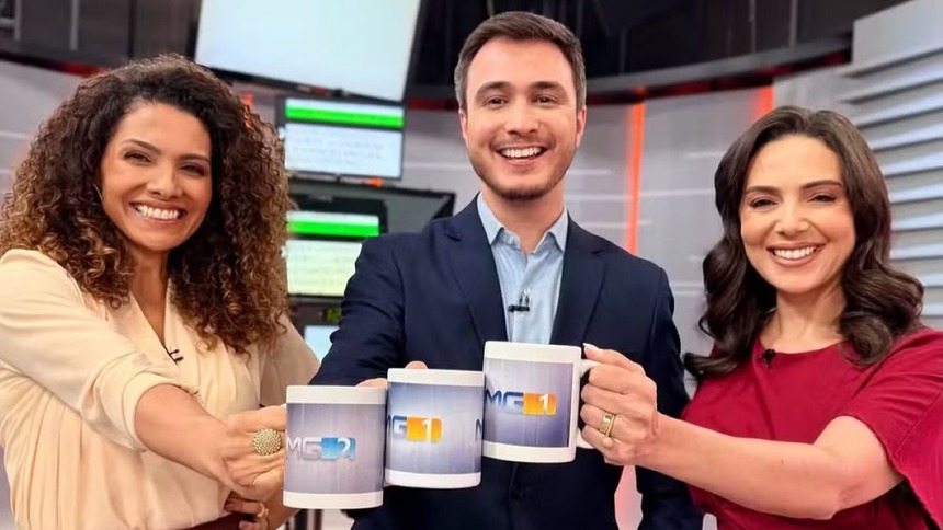 Aline Aguiar, Sérgio Marques e Mara Pinheiro posando sorrindo e segurando canecas dos telejornais da Globo Minas