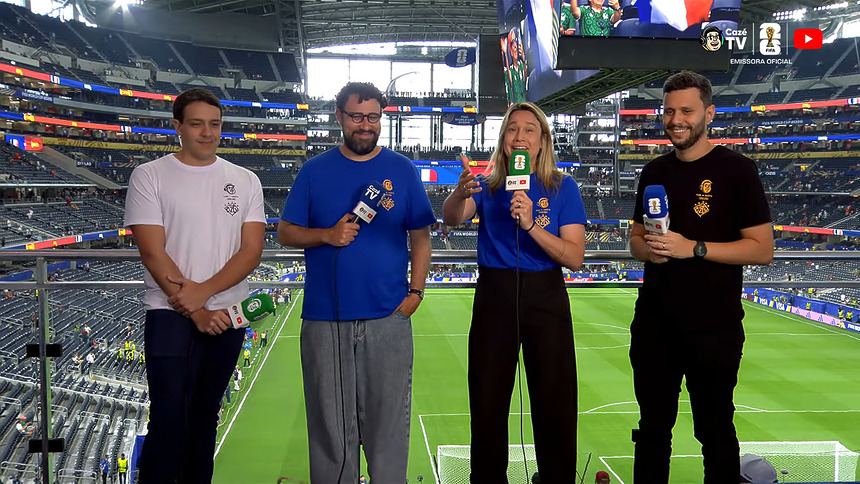 Fernanda Gentil ao lado de outros três apresentadores, em pé na arquibancada do estádio de onde a CazéTV exibiu França x Espanha na Copa do Mundo