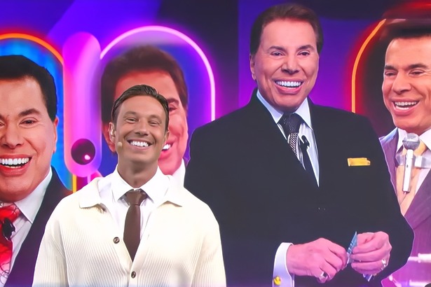 Gabriel Cartolano sorridente em frente ao telão dos 10 Anos Fofocalizando com imagens de Silvio Santos no SBT
