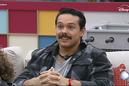 Matheus sorrir sentado no sofá da Casa Do Padrão