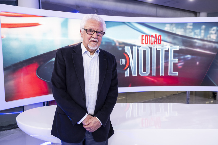 Fernando Mitre em pé na frente do telão do jornal Edição da Noite
