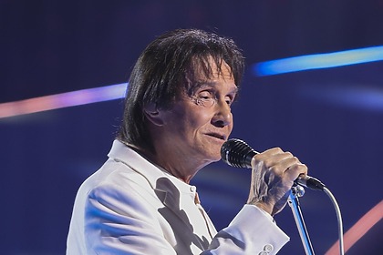 Roberto Carlos segura o microfone no palco de um show