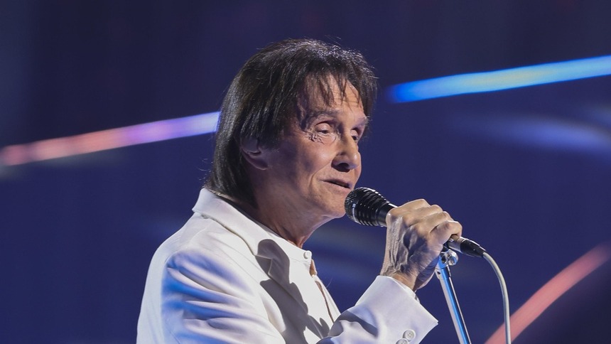 Roberto Carlos segura o microfone no palco de um show