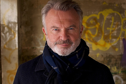Ator Sam Neill, de Jurassic Park, veste sobretudo preto e cachecol
