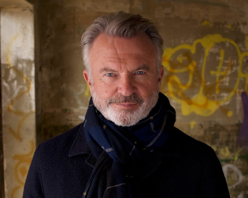 Ator Sam Neill, de Jurassic Park, veste sobretudo preto e cachecol
