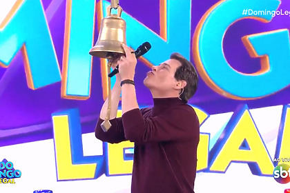 Celso Portiolli beija um sino gigante no cenário do Domingo Legal