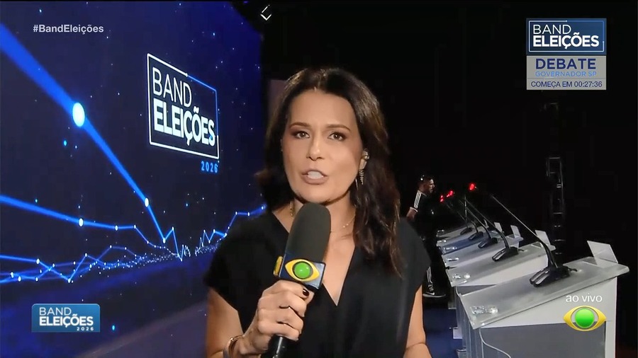Adriana Araújo segura microfone da Band no cenário do Debate no Rio de Janeiro
