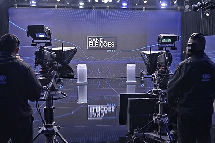 Estúdio Do Debate da Band nas Eleições 2026 um grande telão com cores azuis predominantes e dois púlpitos onde ficam os candidatos