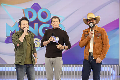 Celso Portiolli sorrir entre Fernando e Sorocaba no palco do Domingo Legal