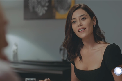 Asya (Cansu Dere), de vestido preto, sorrindo em cena da estreia de Iludida