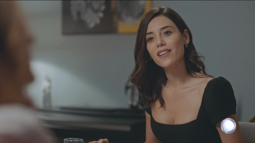 Asya (Cansu Dere), de vestido preto, sorrindo em cena da estreia de Iludida