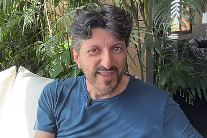 Influenciador Lito Sousa em frente a um pequeno jardim de coqueiros