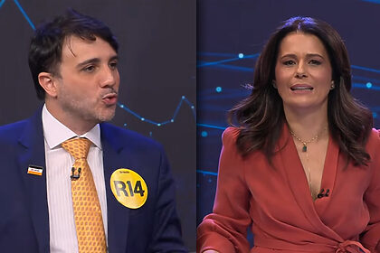 Renan Santos com a boca aberta discursando no seu púlpito do Debate na Band contra Janja, divide tela com a apresentadora Adriana Araujo