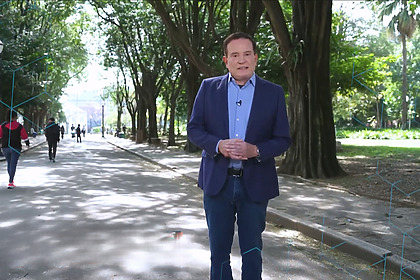 Roberto Cabrini em uma praça vestindo terno caminha em gravação da chamada do Domingo Espetacular