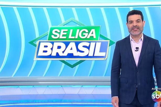 Darlisson Dutra sorrir em frente ao telão do Se Liga Brasil no SBT
