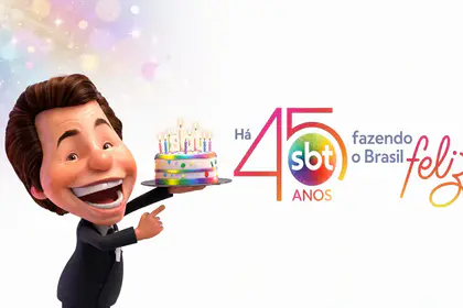 Silvinho segura bolo ao lado do logo comemorativo dos 45 anos do SBT