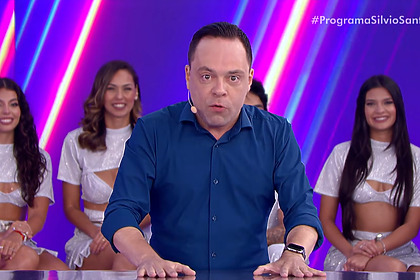 Thiago Gardinali com a mão na mesa do Jogo das 3 Pistas do Programa Silvio Santos no SBT