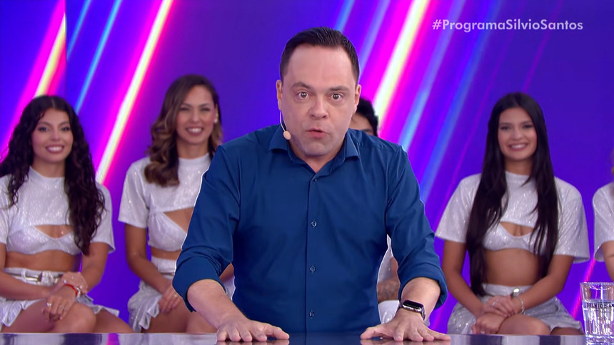 Thiago Gardinali com a mão na mesa do Jogo das 3 Pistas do Programa Silvio Santos no SBT