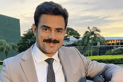 Túlio Amâncio de terno, bigode e sorridente, nos bastidores da GloboNews