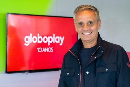 Manuel Belmar sorridente em frente ao logo do Globoplay