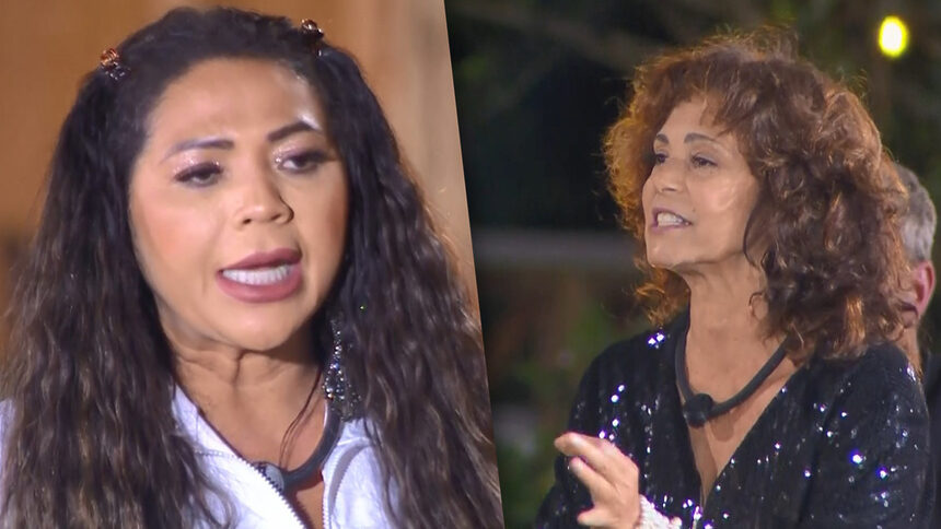 Darlin com a boca aberta brigando com Giovanna que também está com a boca aberta rebatendo. As duas em pé no centro do Aponta Peão na área externa de A Fazenda 18