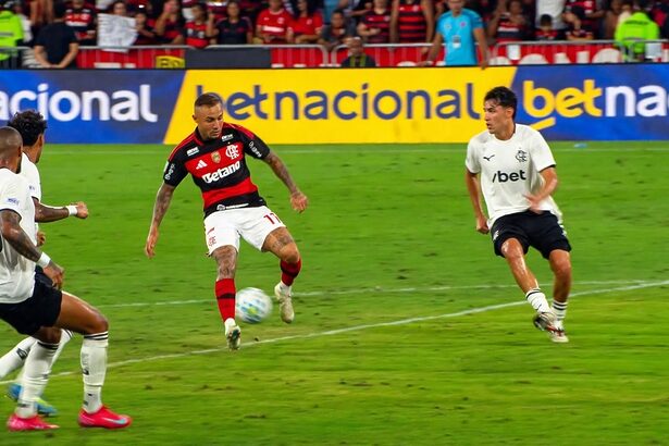 Jogador com camisa do Flamengo dribla bola em campo em transmissão da Globo
