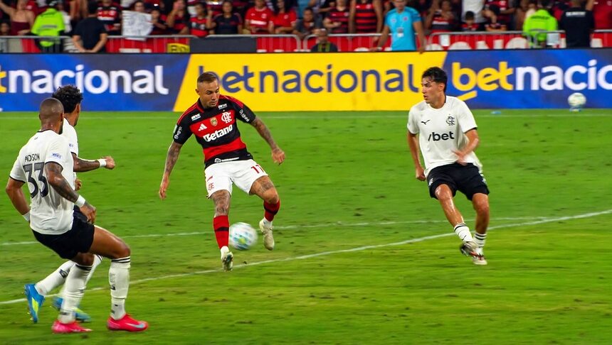 Jogador com camisa do Flamengo dribla bola em campo em transmissão da Globo