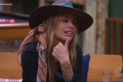 Fran Almeida com chapéu de fazendeira sentada no Rancho do Fazendeiro em A Fazenda