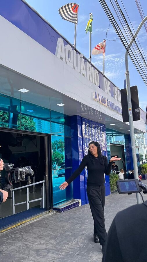 Márcia Fu caminha na fachada do Aquário de São Paulo enquanto grava reportagem para o Hoje em Dia