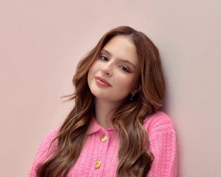 Sophia Valverde de blusa rosa encostada na parede